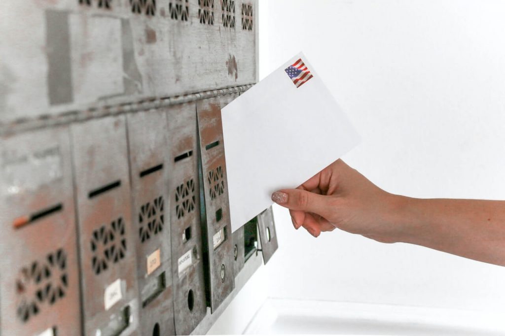 a landlord placing mail into a silver mailbox