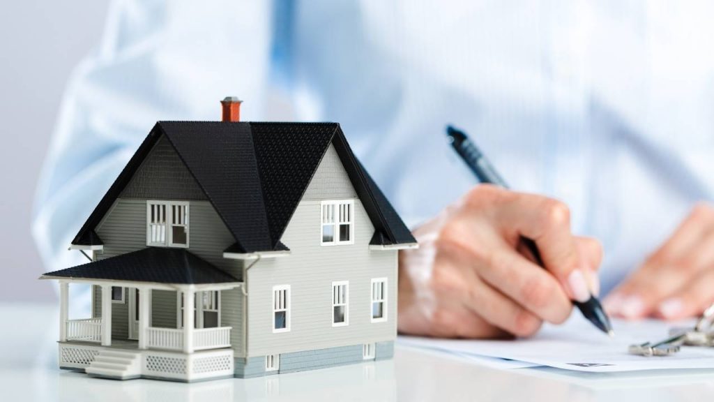 man writing next to house