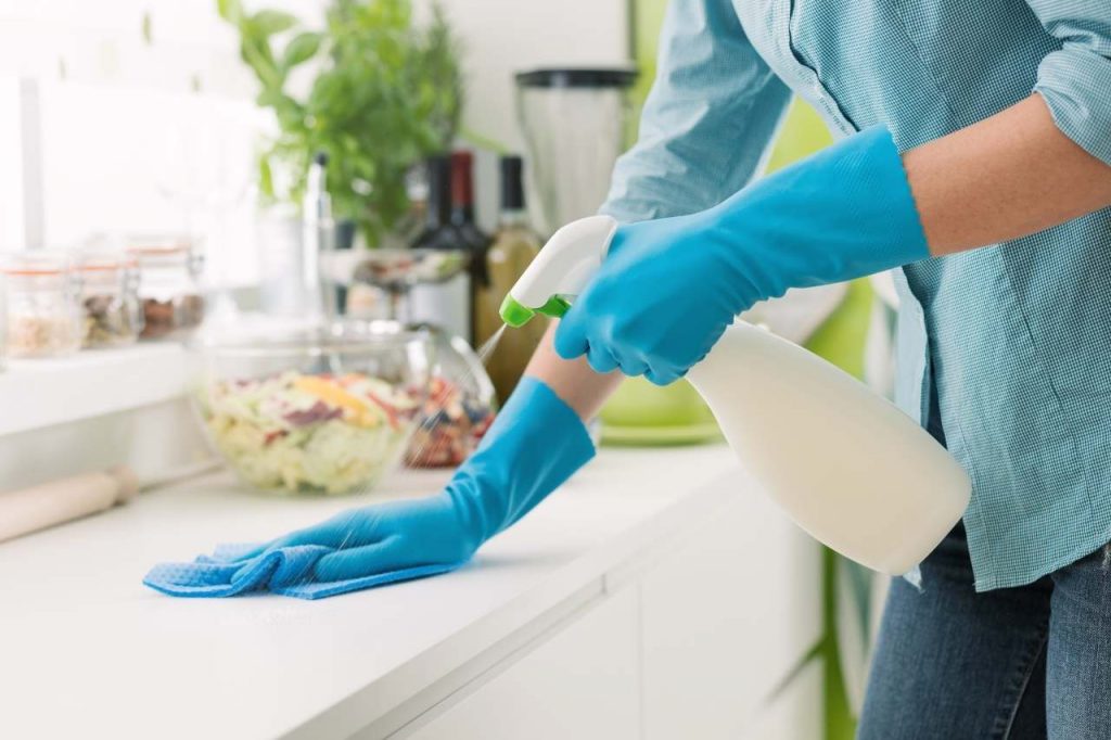 person spraying cleaning product on surface