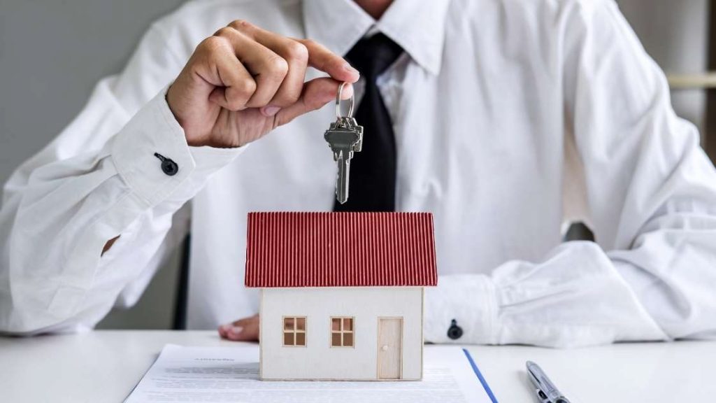 man holding a key over a house