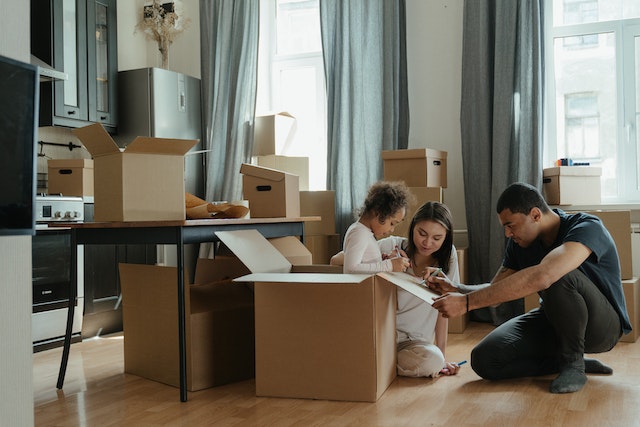 family sitting in the living room opening their moving boxes